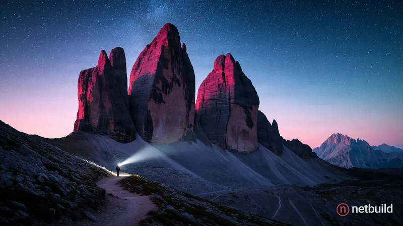 Epic wide-angle landscape photography of three massive rock peaks dominating a starry twilight sky. At the base, a tiny silhouette of a hiker on a roc...